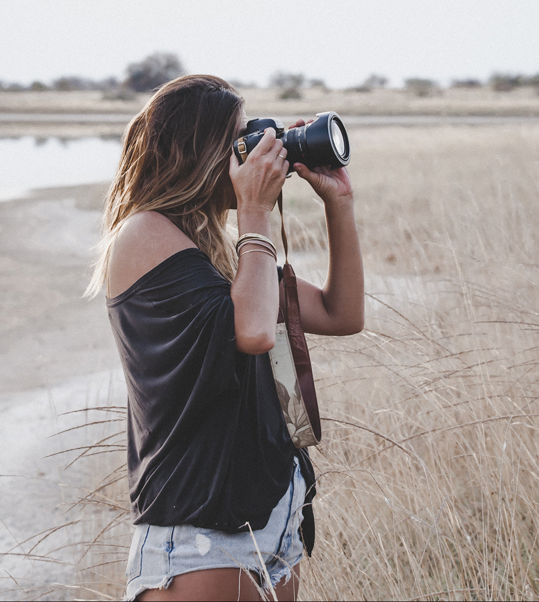 Francoie v taking photographs in Africa's wild bush with a camera and strap.